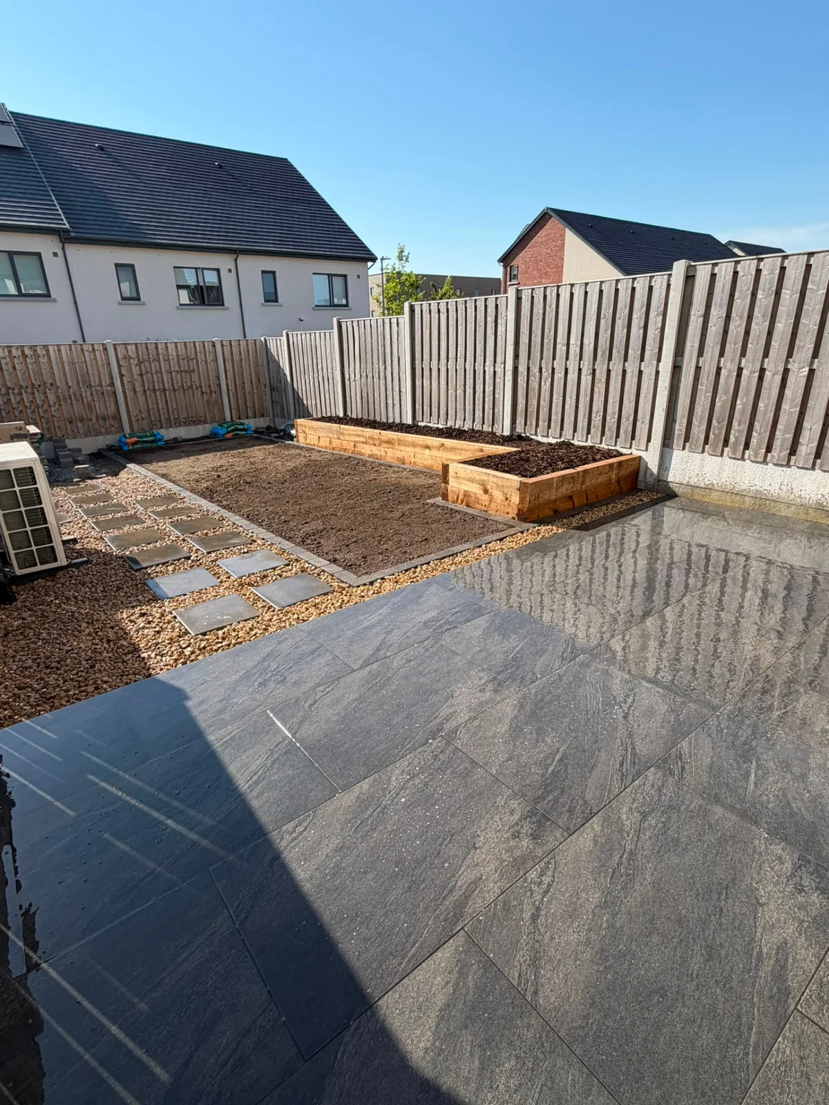 Dark stone patio with stepping-stone path and raised beds